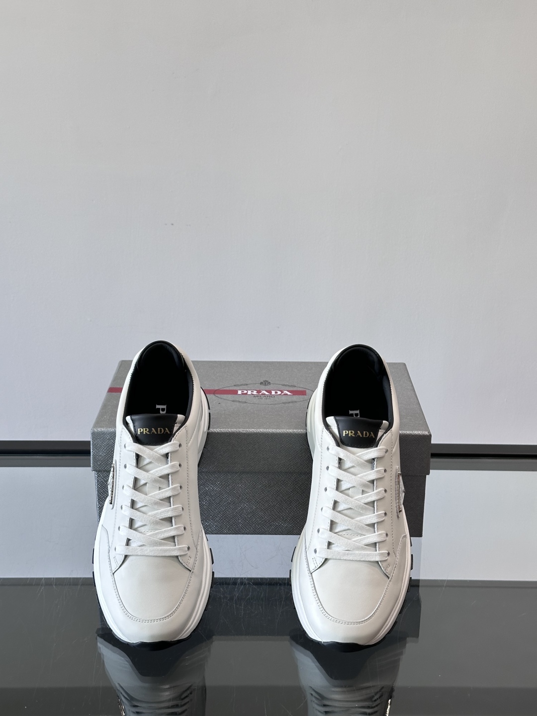 Prada/普拉达 男士新款运动休闲鞋，这款运动鞋鞋面采用进口小牛皮。外侧饰以P家经典金属三角珐琅徽标，