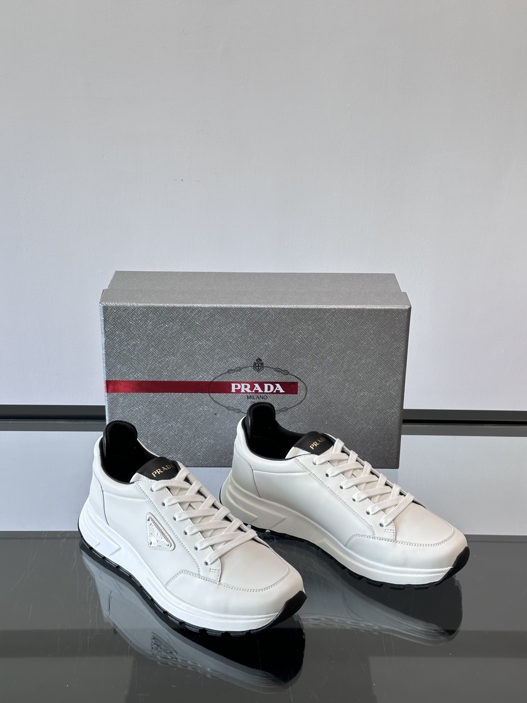 Prada/普拉达 男士新款运动休闲鞋，这款运动鞋鞋面采用进口小牛皮。外侧饰以P家经典金属三角珐琅徽标，