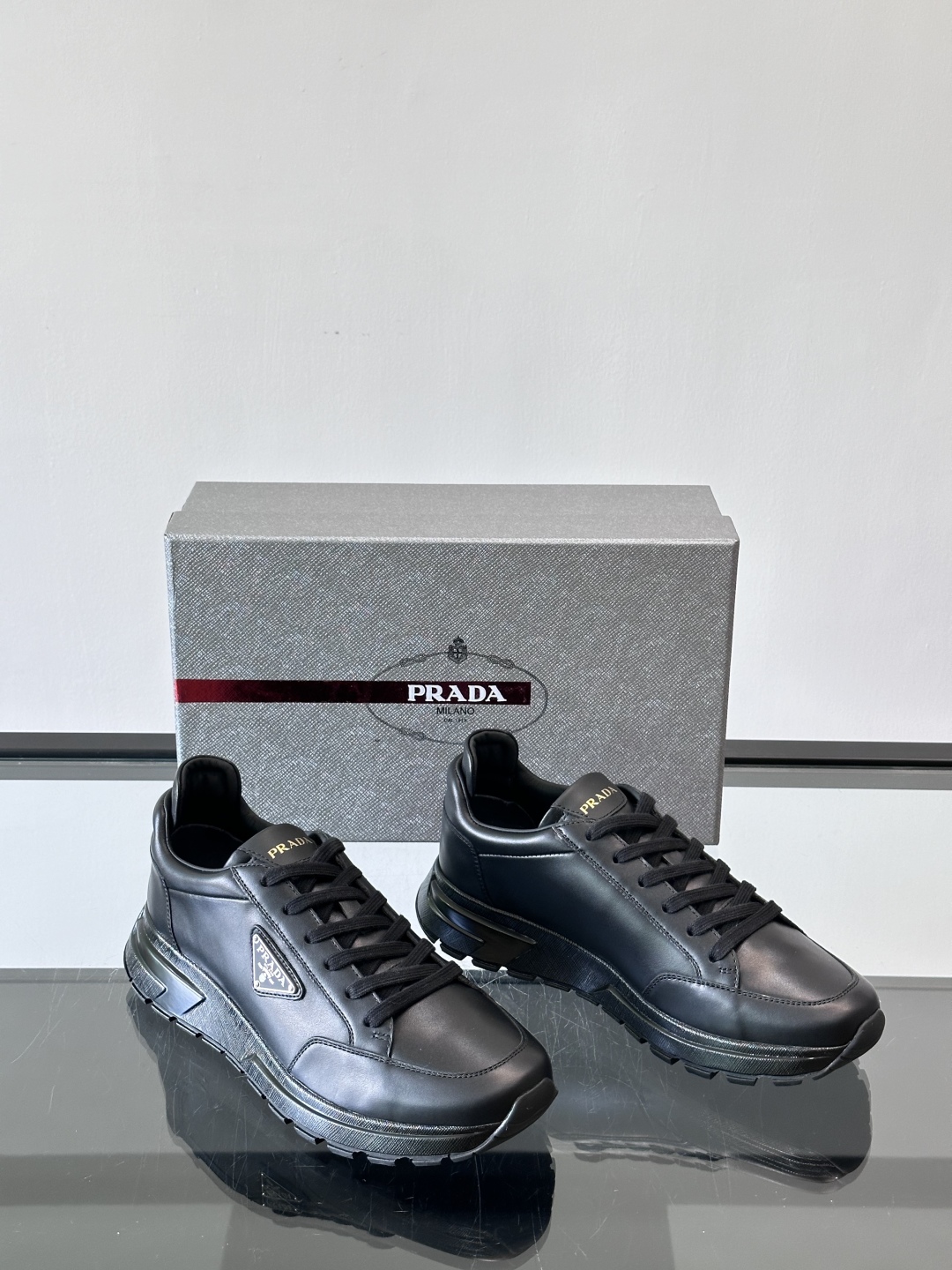 Prada/普拉达 男士新款运动休闲鞋，这款运动鞋鞋面采用进口小牛皮。外侧饰以P家经典金属三角珐琅徽标，
