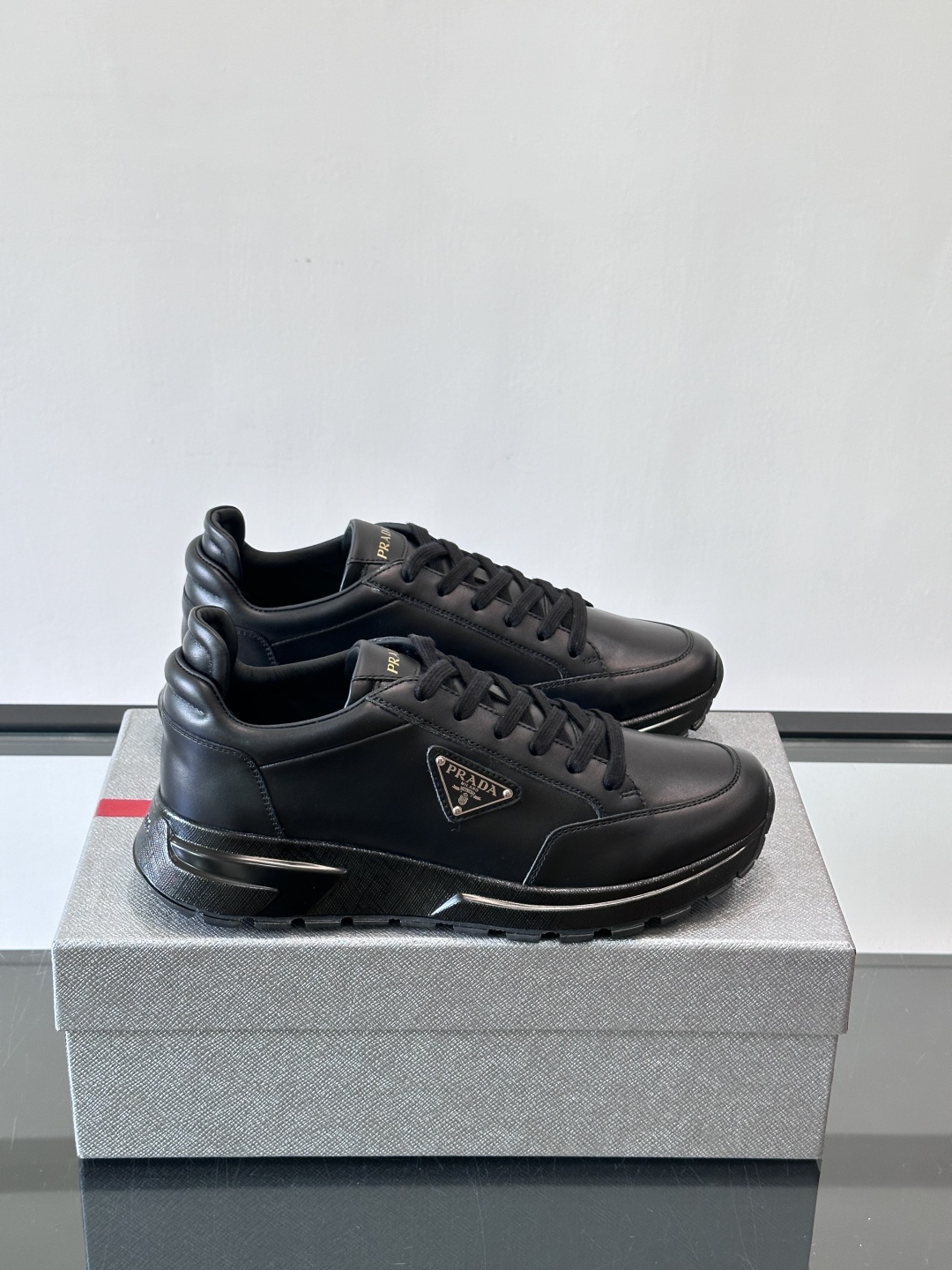 Prada/普拉达 男士新款运动休闲鞋，这款运动鞋鞋面采用进口小牛皮。外侧饰以P家经典金属三角珐琅徽标，