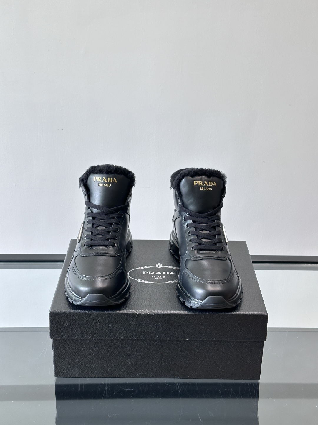 PRADA/普拉达 男士新款高帮运动鞋，这款厚底运动鞋采用牛皮鞋面制成，搭配加厚橡胶发泡中底拼接前后包裹