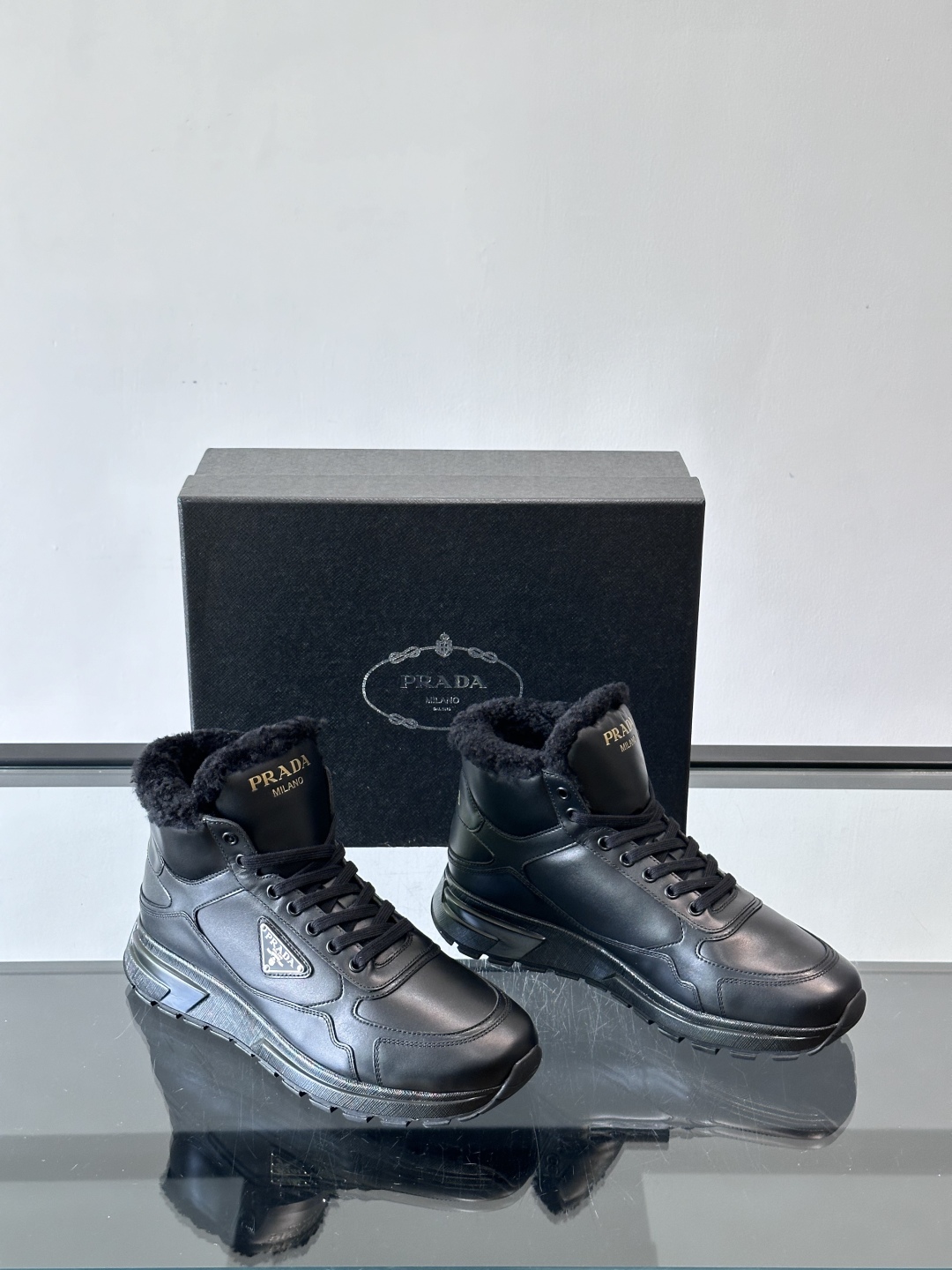 PRADA/普拉达 男士新款高帮运动鞋，这款厚底运动鞋采用牛皮鞋面制成，搭配加厚橡胶发泡中底拼接前后包裹