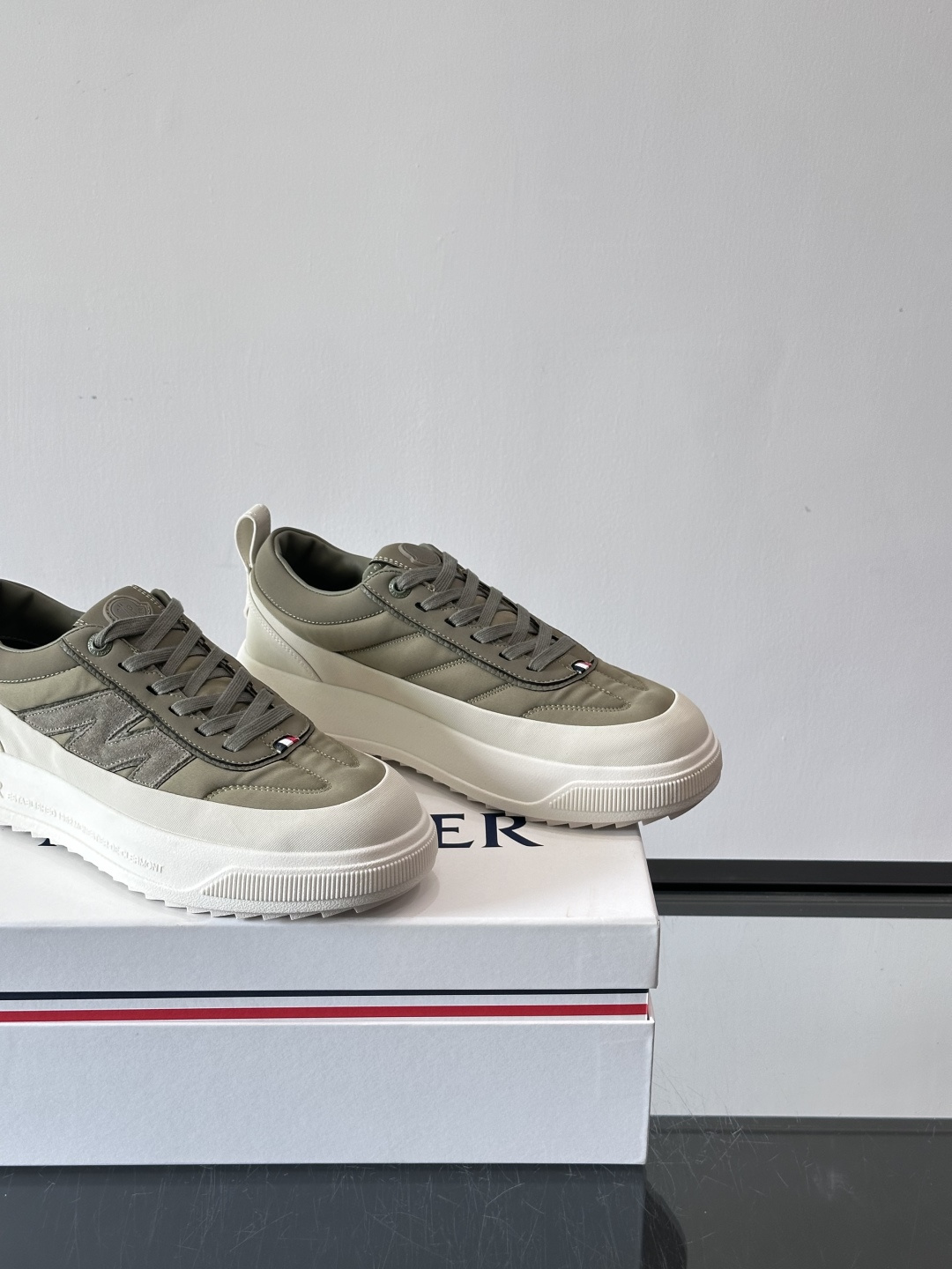 Moncler这款休闲运动鞋，主打简约百搭风，鞋面拼接米白+浅灰，蓝色橡胶鞋底和侧边点缀超有活力。鞋舌和