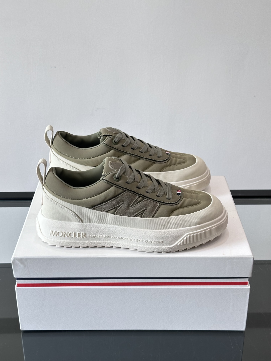 Moncler这款休闲运动鞋，主打简约百搭风，鞋面拼接米白+浅灰，蓝色橡胶鞋底和侧边点缀超有活力。鞋舌和