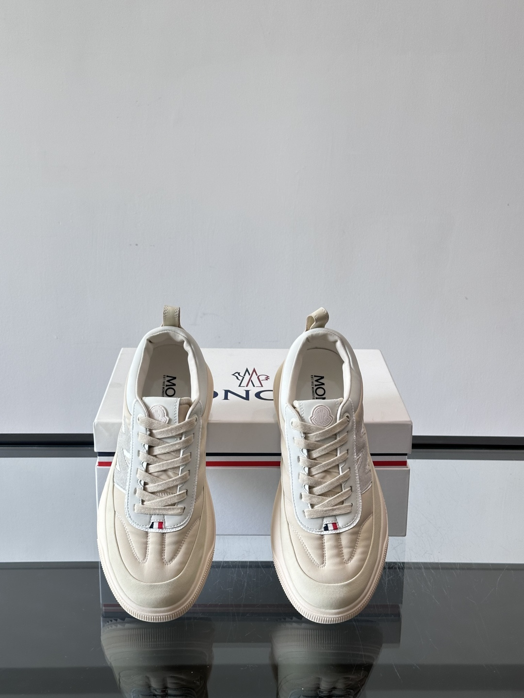 Moncler这款休闲运动鞋，主打简约百搭风，鞋面拼接米白+浅灰，蓝色橡胶鞋底和侧边点缀超有活力。鞋舌和