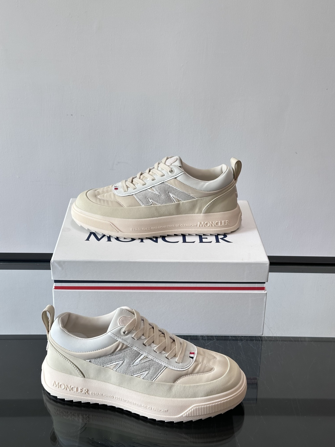 Moncler这款休闲运动鞋，主打简约百搭风，鞋面拼接米白+浅灰，蓝色橡胶鞋底和侧边点缀超有活力。鞋舌和