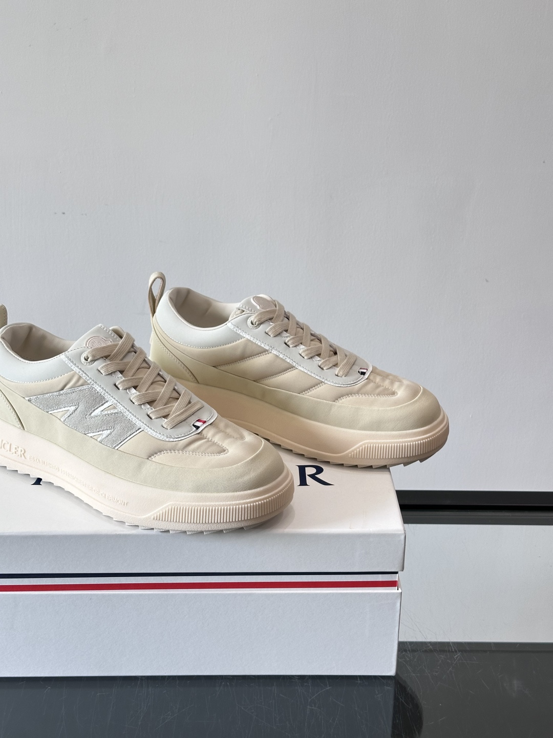 Moncler这款休闲运动鞋，主打简约百搭风，鞋面拼接米白+浅灰，蓝色橡胶鞋底和侧边点缀超有活力。鞋舌和