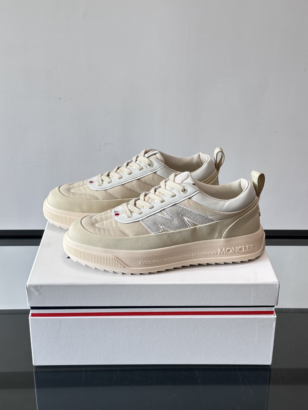 Moncler这款休闲运动鞋，主打简约百搭风，鞋面拼接米白+浅灰，蓝色橡胶鞋底和侧边点缀超有活力。鞋舌和