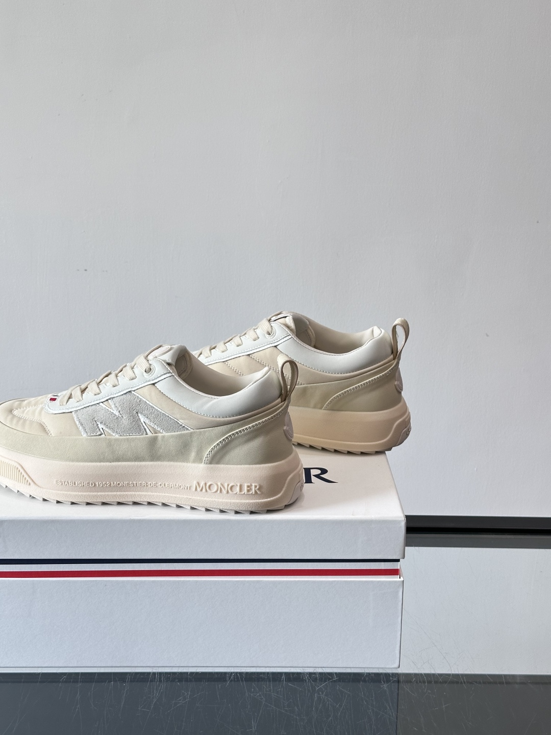 Moncler这款休闲运动鞋，主打简约百搭风，鞋面拼接米白+浅灰，蓝色橡胶鞋底和侧边点缀超有活力。鞋舌和