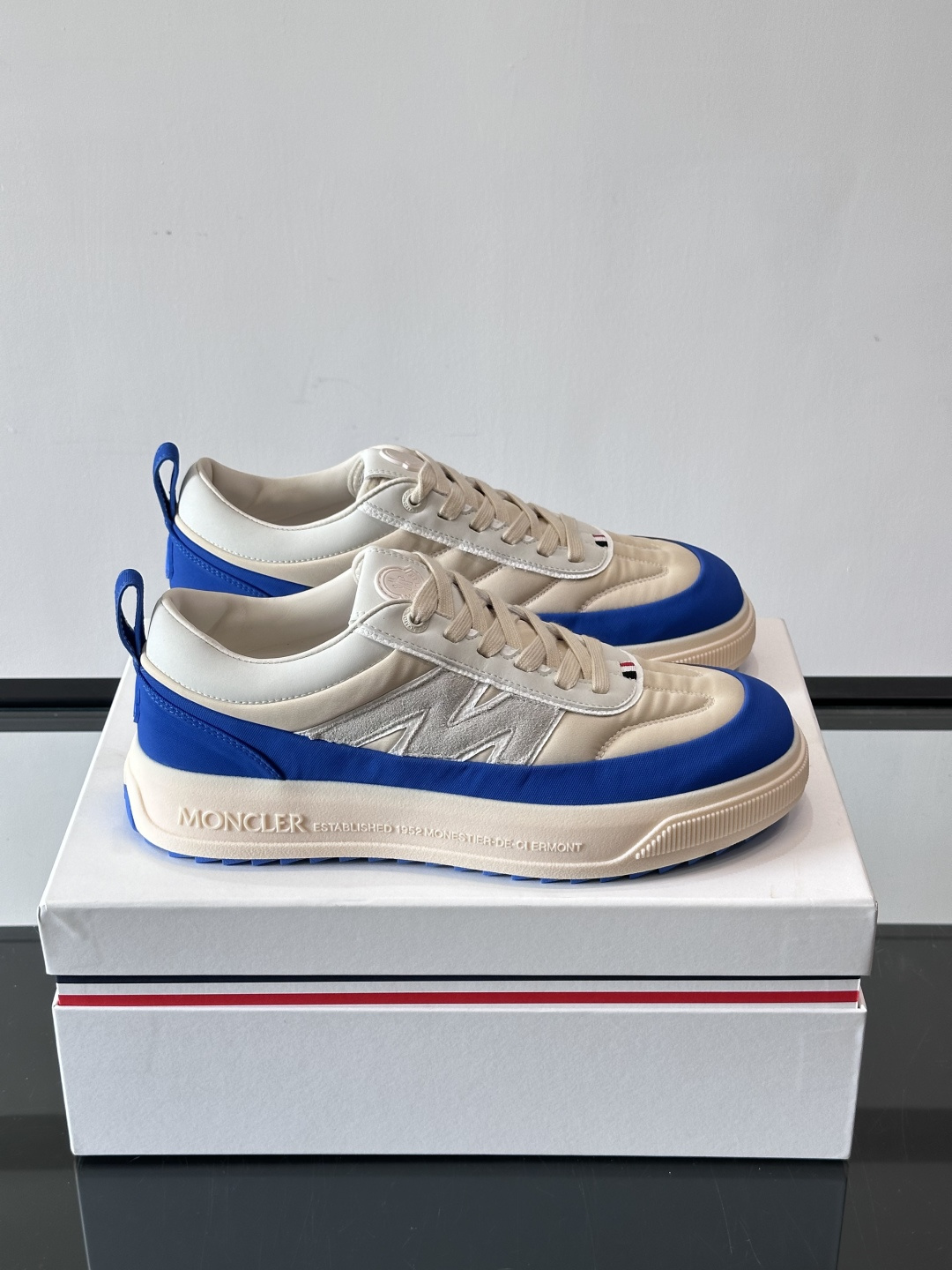 Moncler这款休闲运动鞋，主打简约百搭风，鞋面拼接米白+浅灰，蓝色橡胶鞋底和侧边点缀超有活力。鞋舌和
