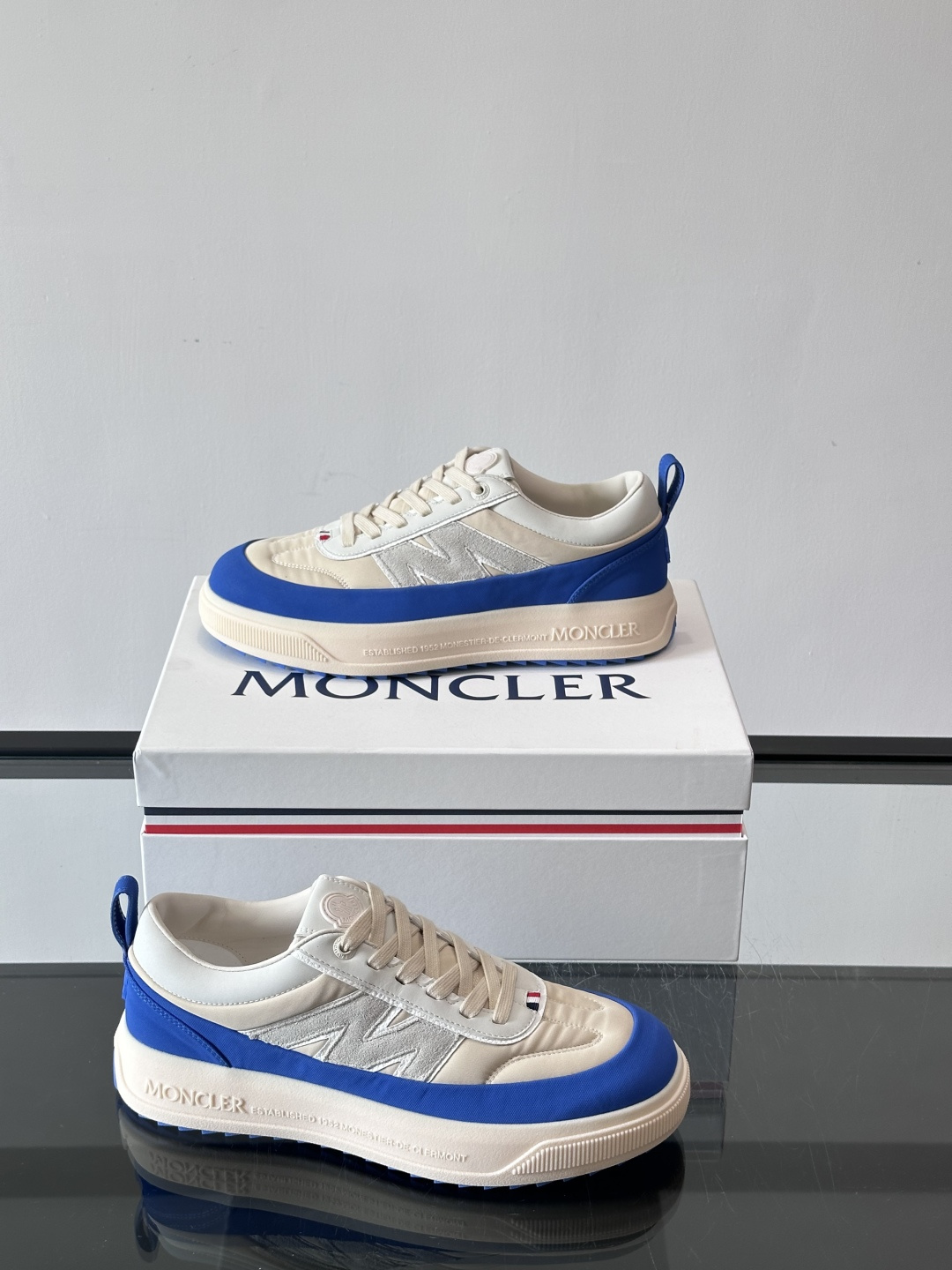 Moncler这款休闲运动鞋，主打简约百搭风，鞋面拼接米白+浅灰，蓝色橡胶鞋底和侧边点缀超有活力。鞋舌和