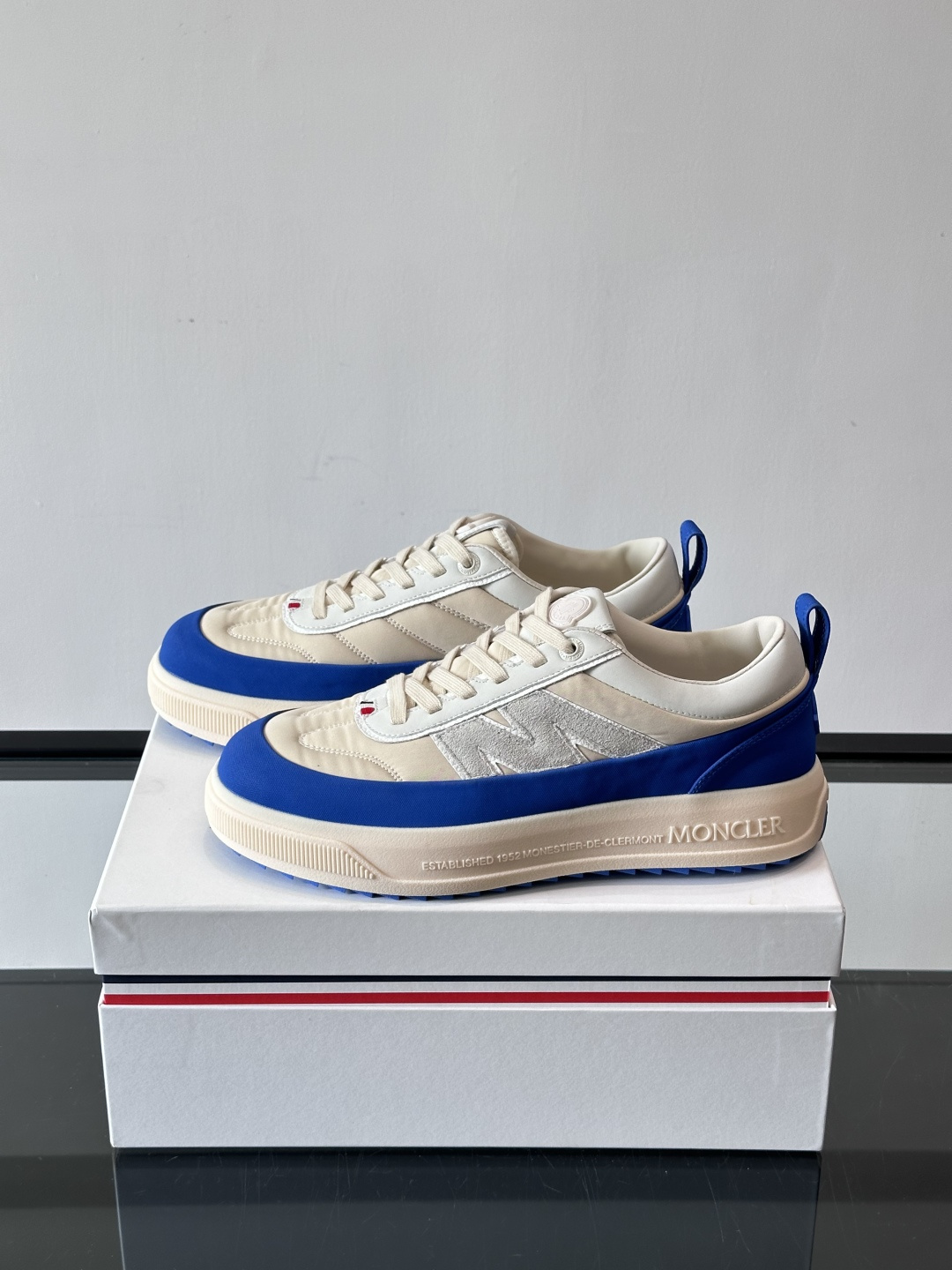 Moncler这款休闲运动鞋，主打简约百搭风，鞋面拼接米白+浅灰，蓝色橡胶鞋底和侧边点缀超有活力。鞋舌和