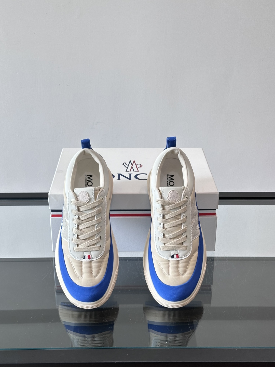 Moncler这款休闲运动鞋，主打简约百搭风，鞋面拼接米白+浅灰，蓝色橡胶鞋底和侧边点缀超有活力。鞋舌和