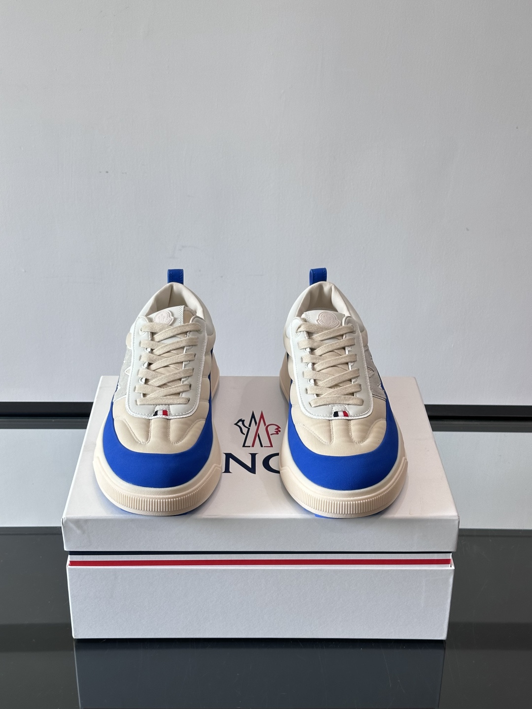 Moncler这款休闲运动鞋，主打简约百搭风，鞋面拼接米白+浅灰，蓝色橡胶鞋底和侧边点缀超有活力。鞋舌和