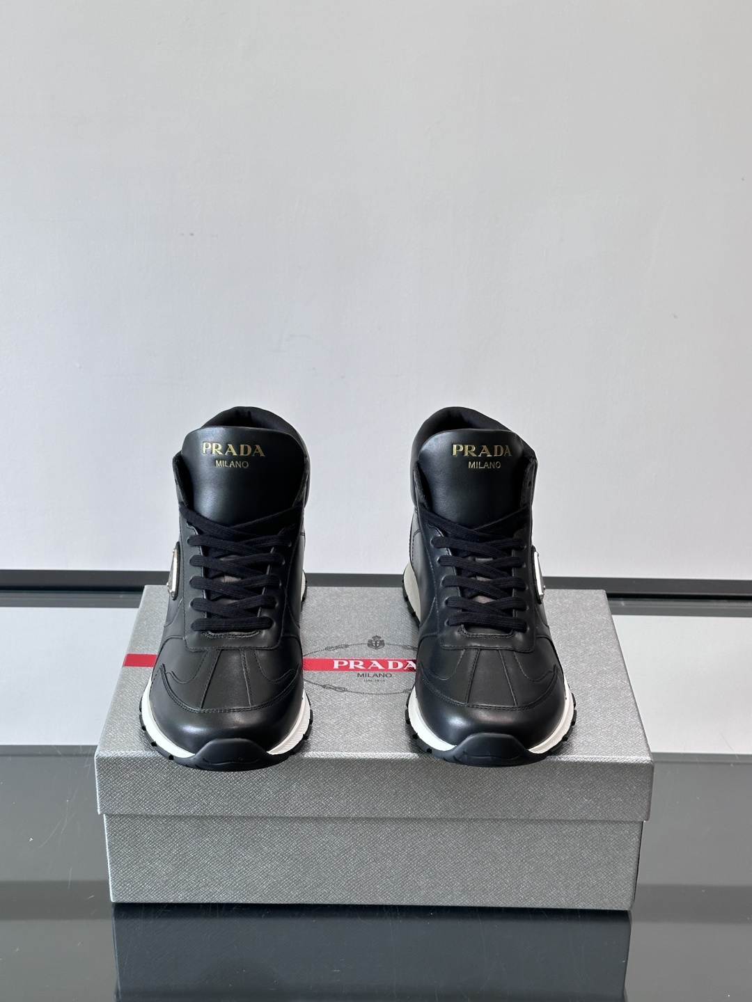 PRADA/普拉达 男士新款高帮运动鞋，这款厚底运动鞋采用牛皮鞋面制成，搭配加厚橡胶发泡中底拼接前后包裹