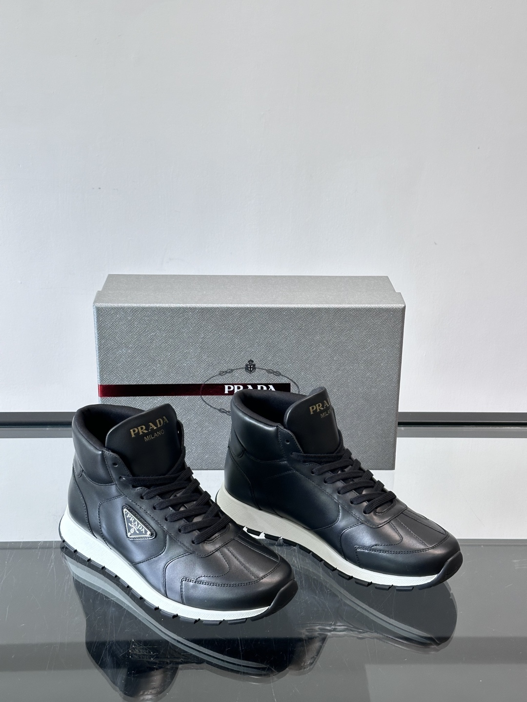PRADA/普拉达 男士新款高帮运动鞋，这款厚底运动鞋采用牛皮鞋面制成，搭配加厚橡胶发泡中底拼接前后包裹