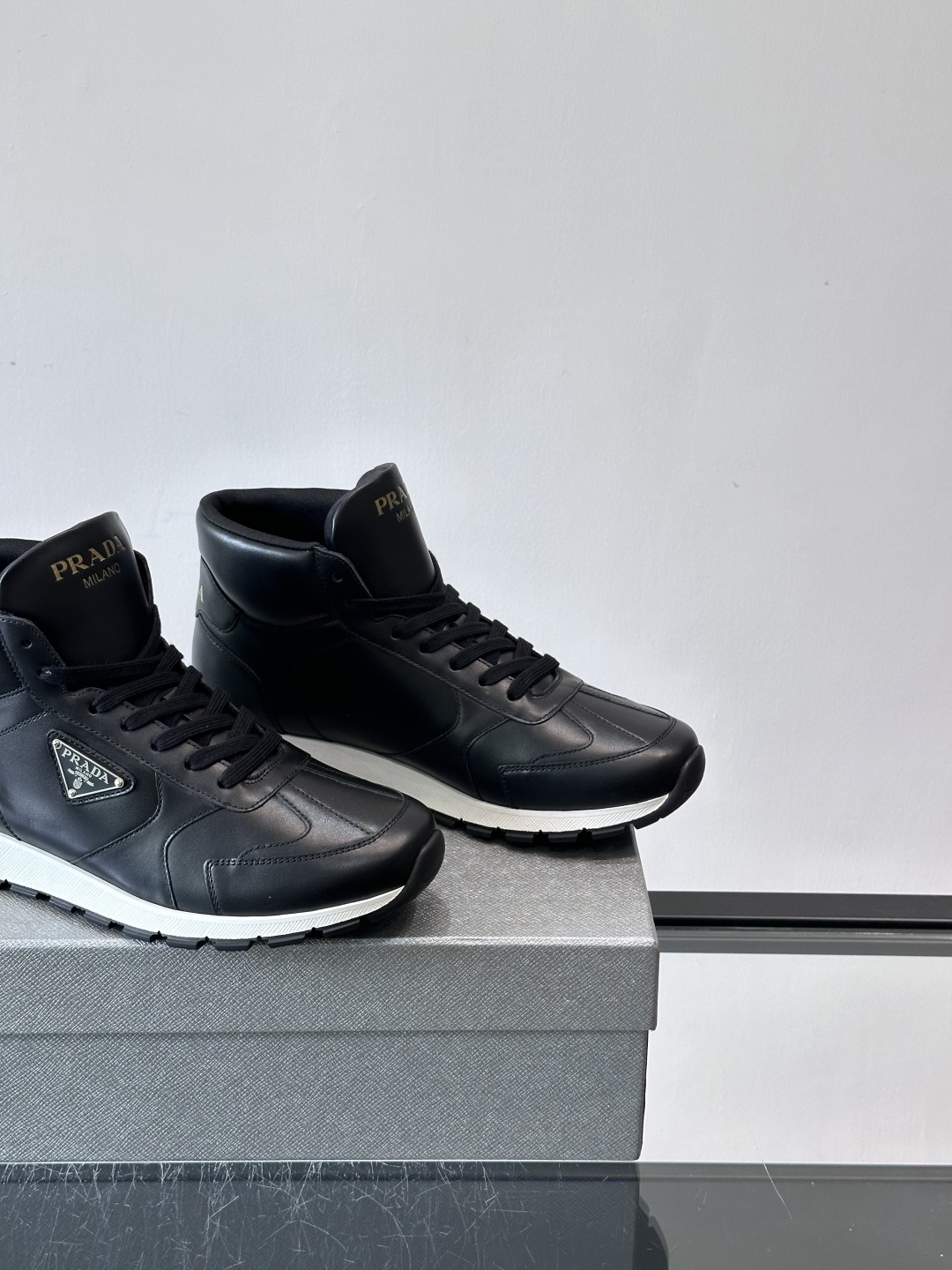PRADA/普拉达 男士新款高帮运动鞋，这款厚底运动鞋采用牛皮鞋面制成，搭配加厚橡胶发泡中底拼接前后包裹