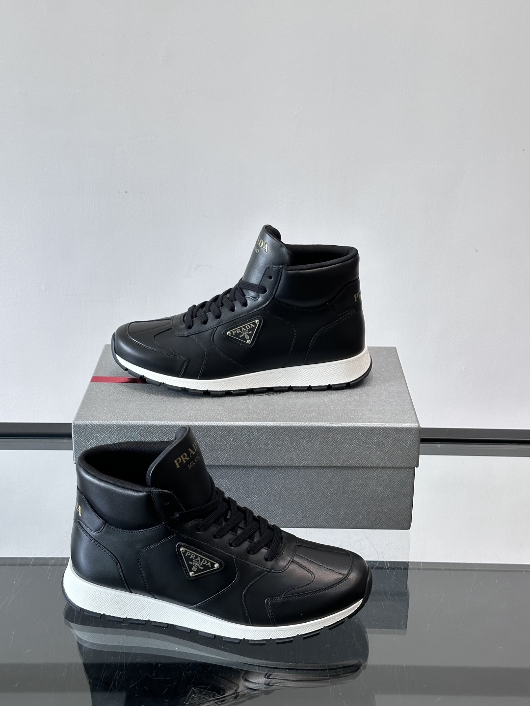 PRADA/普拉达 男士新款高帮运动鞋，这款厚底运动鞋采用牛皮鞋面制成，搭配加厚橡胶发泡中底拼接前后包裹