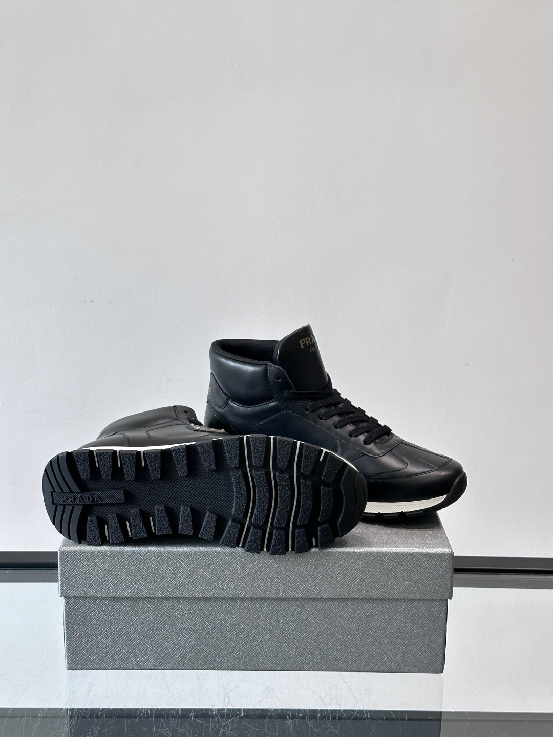 PRADA/普拉达 男士新款高帮运动鞋，这款厚底运动鞋采用牛皮鞋面制成，搭配加厚橡胶发泡中底拼接前后包裹