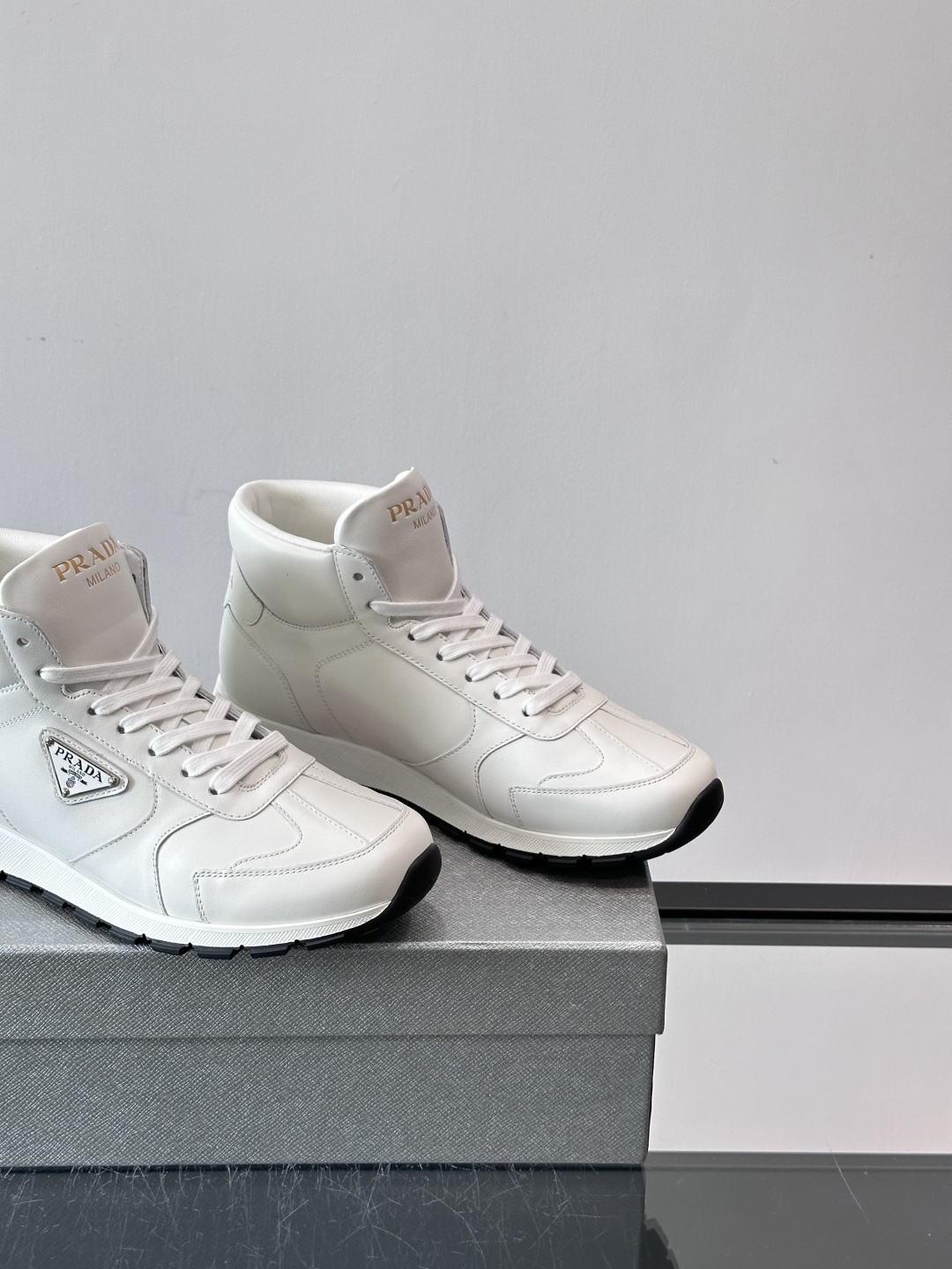 PRADA/普拉达 男士新款高帮运动鞋，这款厚底运动鞋采用牛皮鞋面制成，搭配加厚橡胶发泡中底拼接前后包裹