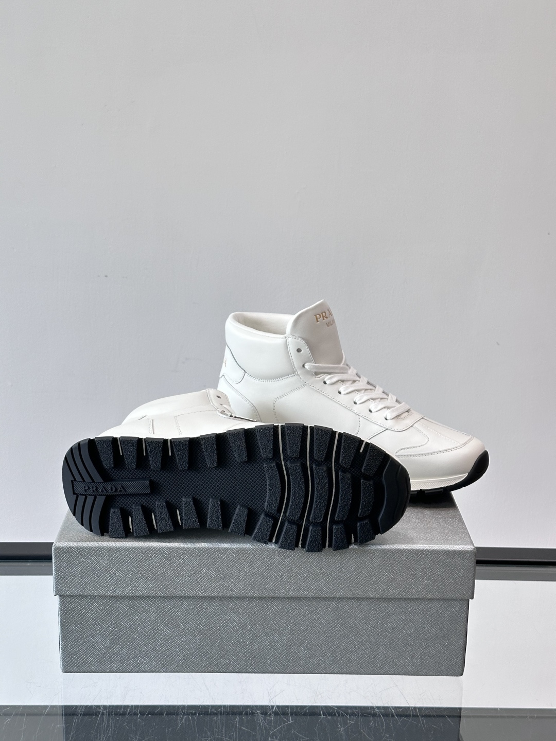 PRADA/普拉达 男士新款高帮运动鞋，这款厚底运动鞋采用牛皮鞋面制成，搭配加厚橡胶发泡中底拼接前后包裹