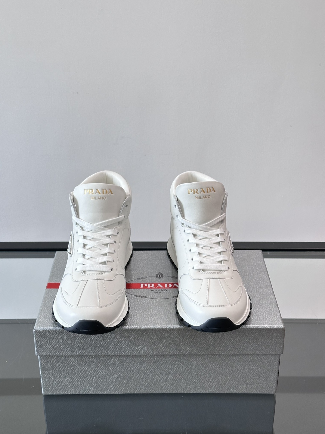 PRADA/普拉达 男士新款高帮运动鞋，这款厚底运动鞋采用牛皮鞋面制成，搭配加厚橡胶发泡中底拼接前后包裹