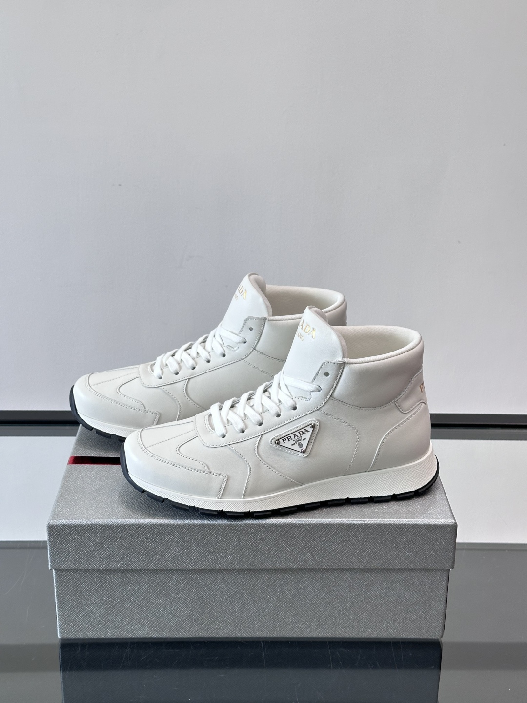 PRADA/普拉达 男士新款高帮运动鞋，这款厚底运动鞋采用牛皮鞋面制成，搭配加厚橡胶发泡中底拼接前后包裹