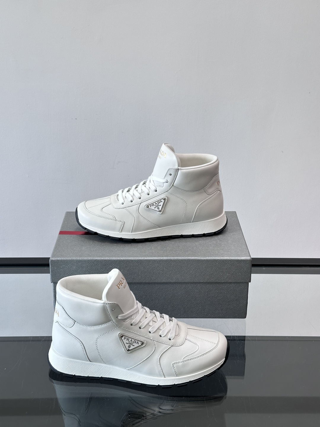 PRADA/普拉达 男士新款高帮运动鞋，这款厚底运动鞋采用牛皮鞋面制成，搭配加厚橡胶发泡中底拼接前后包裹