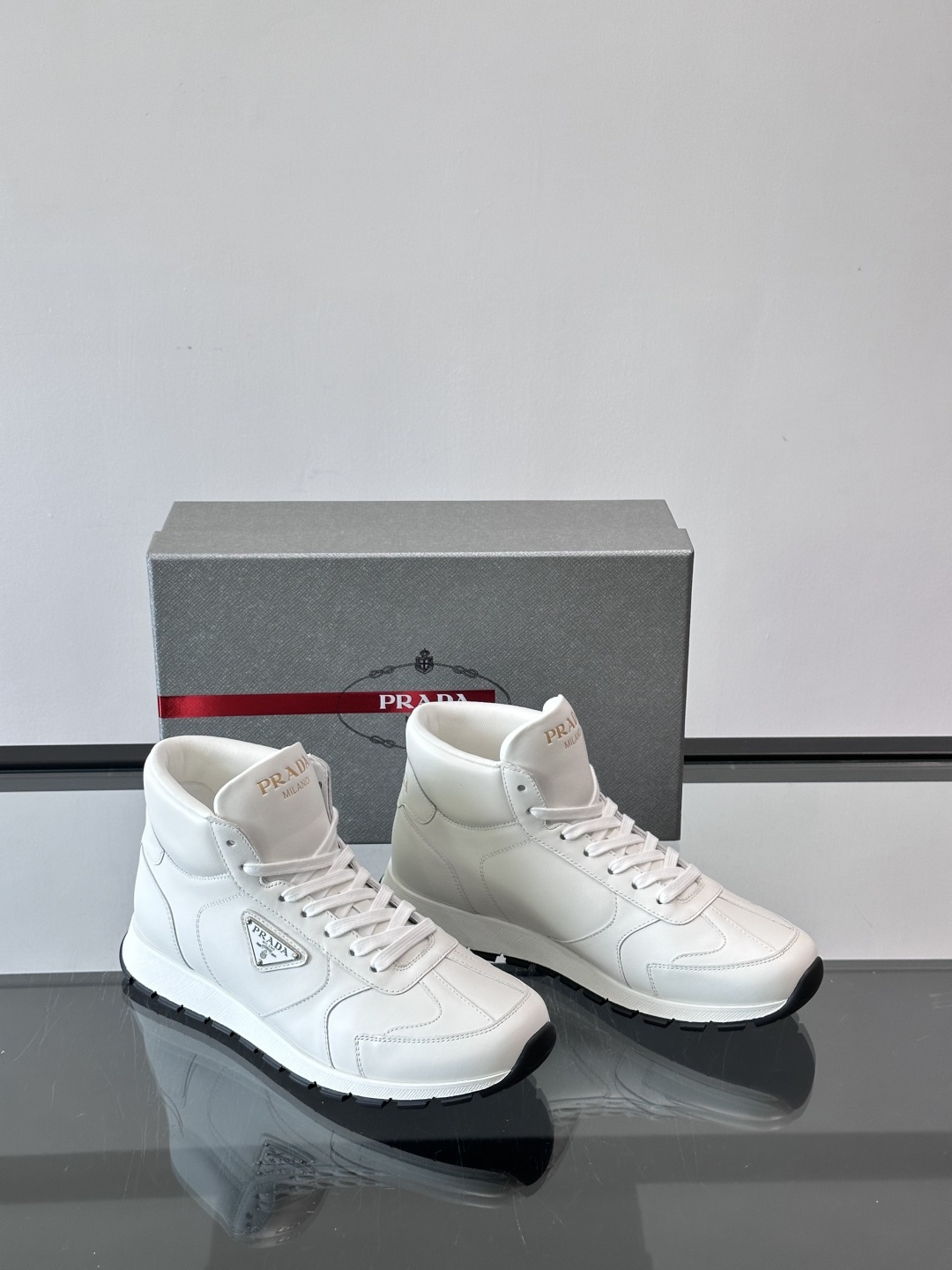 PRADA/普拉达 男士新款高帮运动鞋，这款厚底运动鞋采用牛皮鞋面制成，搭配加厚橡胶发泡中底拼接前后包裹