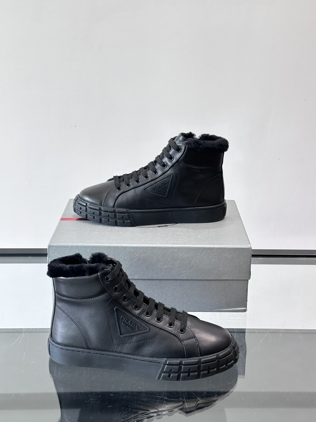 PRADA/普拉达 男士新款高帮运动鞋，这款厚底运动鞋采用牛皮鞋面制成，搭配加厚橡胶发泡中底拼接前后包裹
