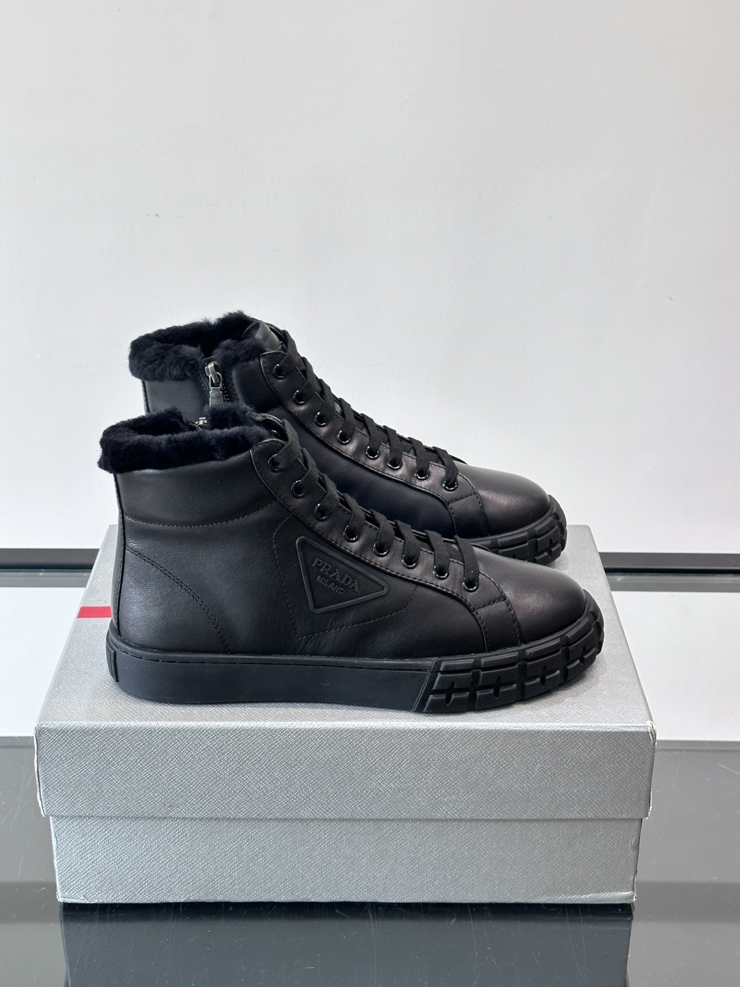 PRADA/普拉达 男士新款高帮运动鞋，这款厚底运动鞋采用牛皮鞋面制成，搭配加厚橡胶发泡中底拼接前后包裹