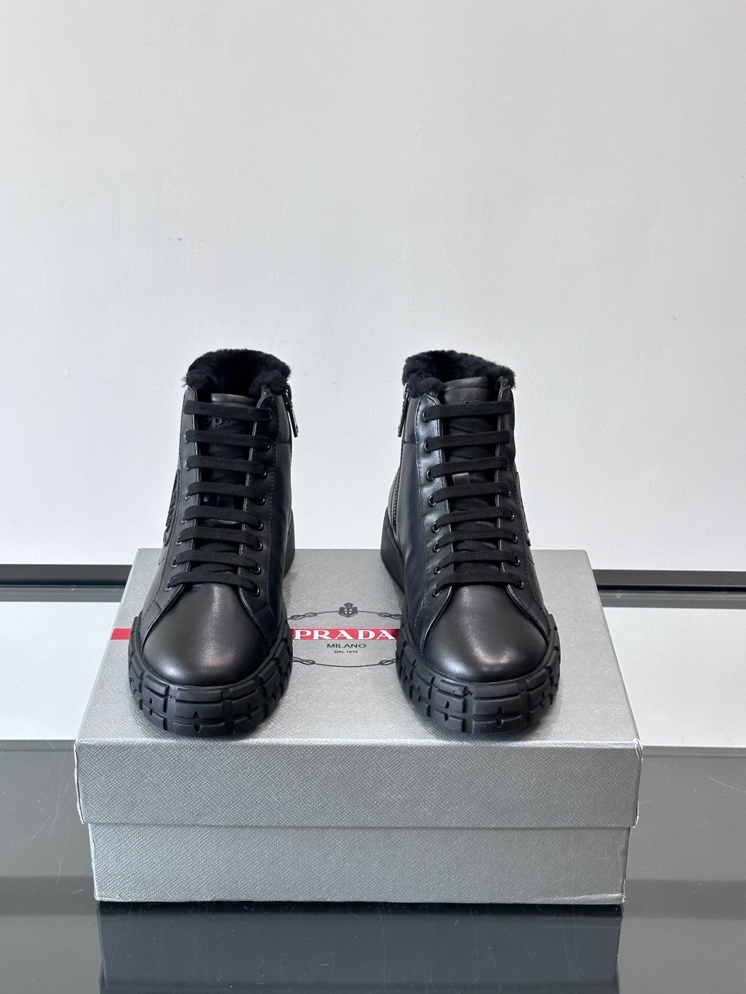 PRADA/普拉达 男士新款高帮运动鞋，这款厚底运动鞋采用牛皮鞋面制成，搭配加厚橡胶发泡中底拼接前后包裹