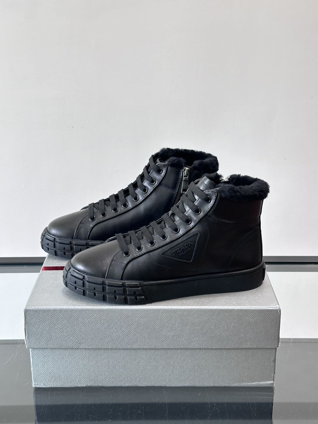 PRADA/普拉达 男士新款高帮运动鞋，这款厚底运动鞋采用牛皮鞋面制成，搭配加厚橡胶发泡中底拼接前后包裹