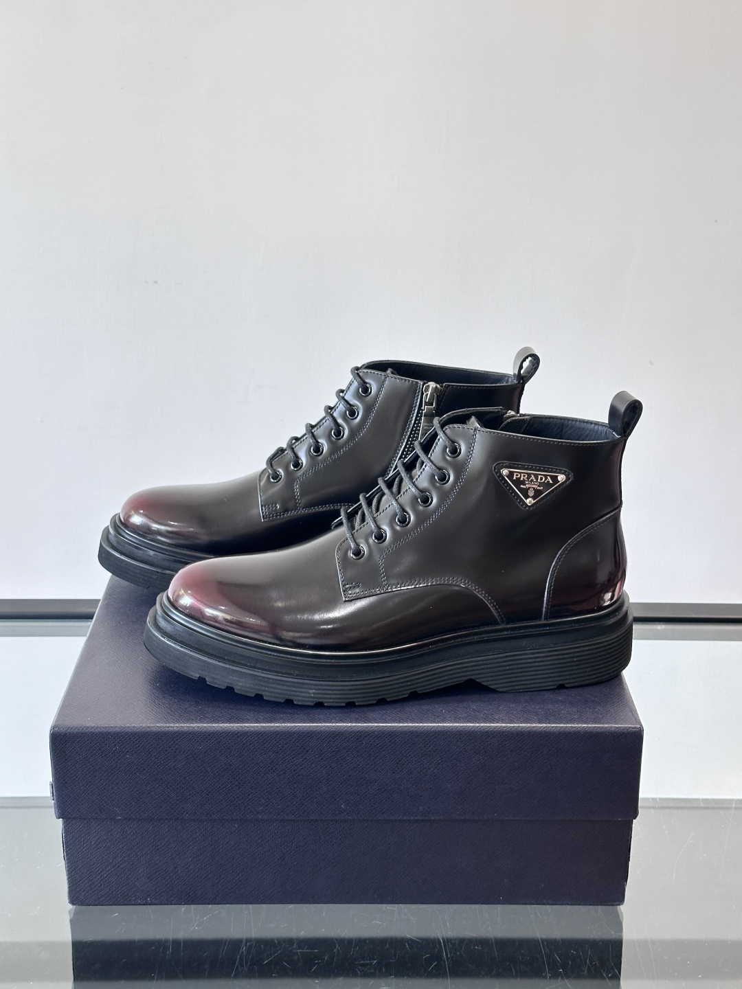 Prada这款男士商务马丁靴，选用优质牛皮，鞋面光滑有质感，搭配经典三角标，低调又有辦识度。厚底橡胶鞋底