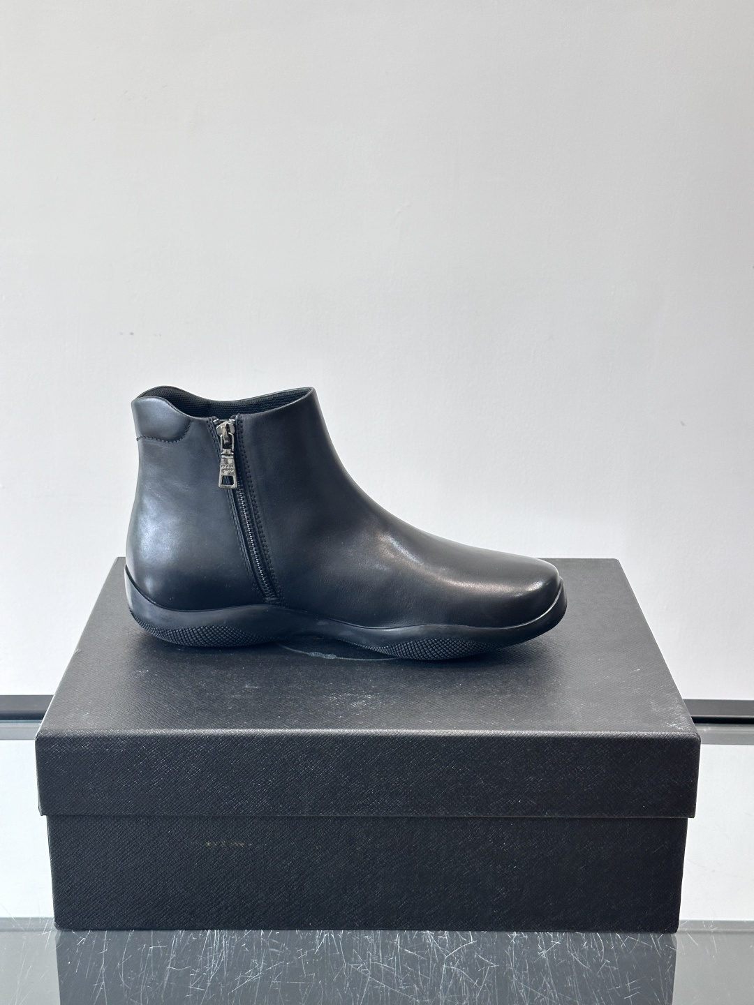 Prada黑色真皮切尔西靴这款黑色真皮切尔西靴选用优质牛皮，鞋面光滑细腻，质感满。经典套脚设计+侧边拉链