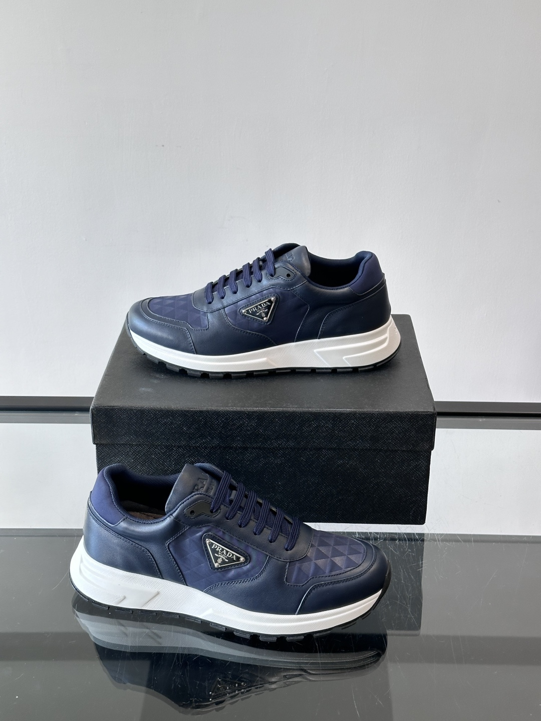Prada 男士休闲运动鞋。采用麂皮与尼龙面料拼接，质感柔软又耐用，低调奢华。鞋侧三角徽标超有辨识度，橡