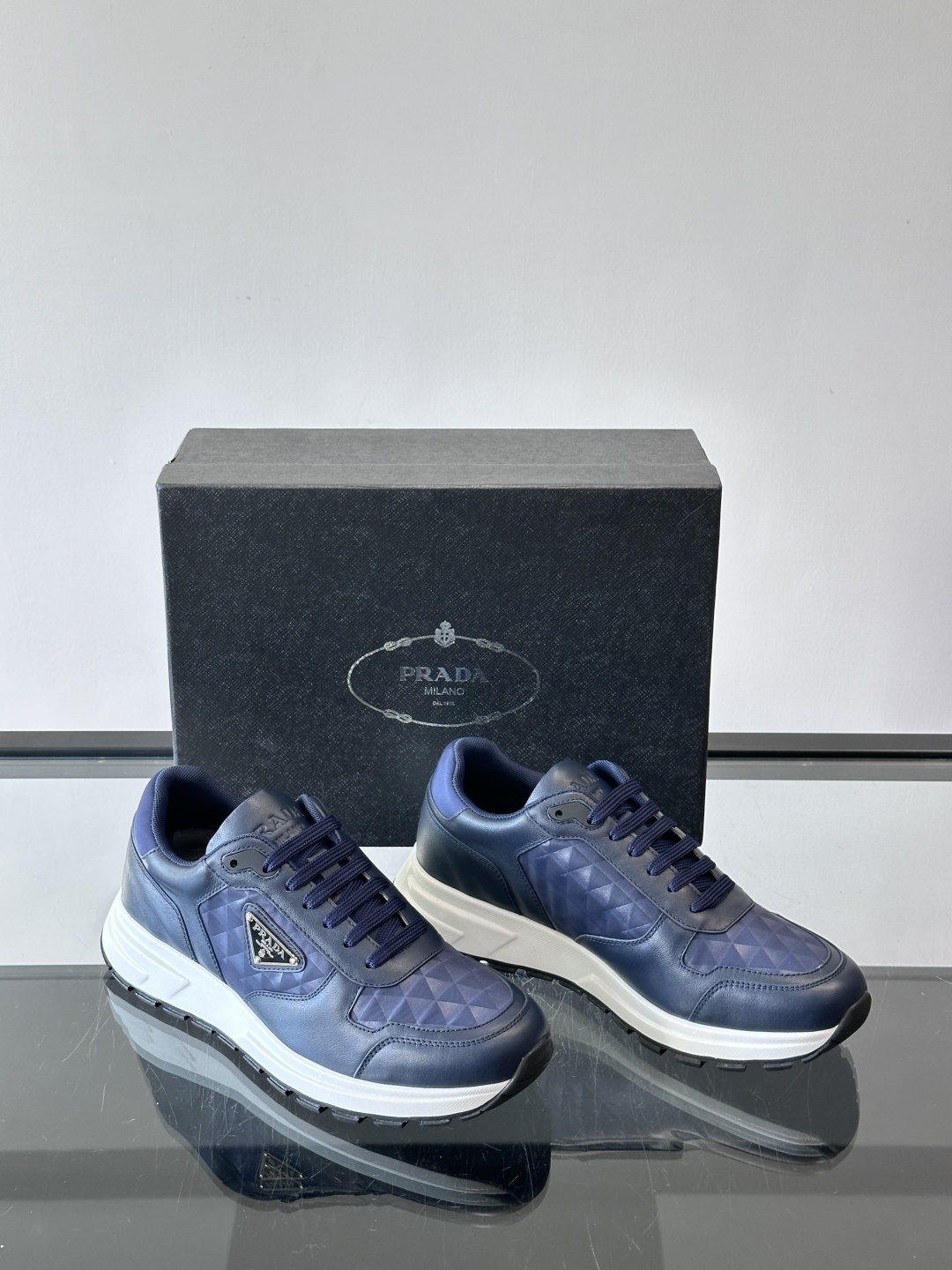 Prada 男士休闲运动鞋。采用麂皮与尼龙面料拼接，质感柔软又耐用，低调奢华。鞋侧三角徽标超有辨识度，橡