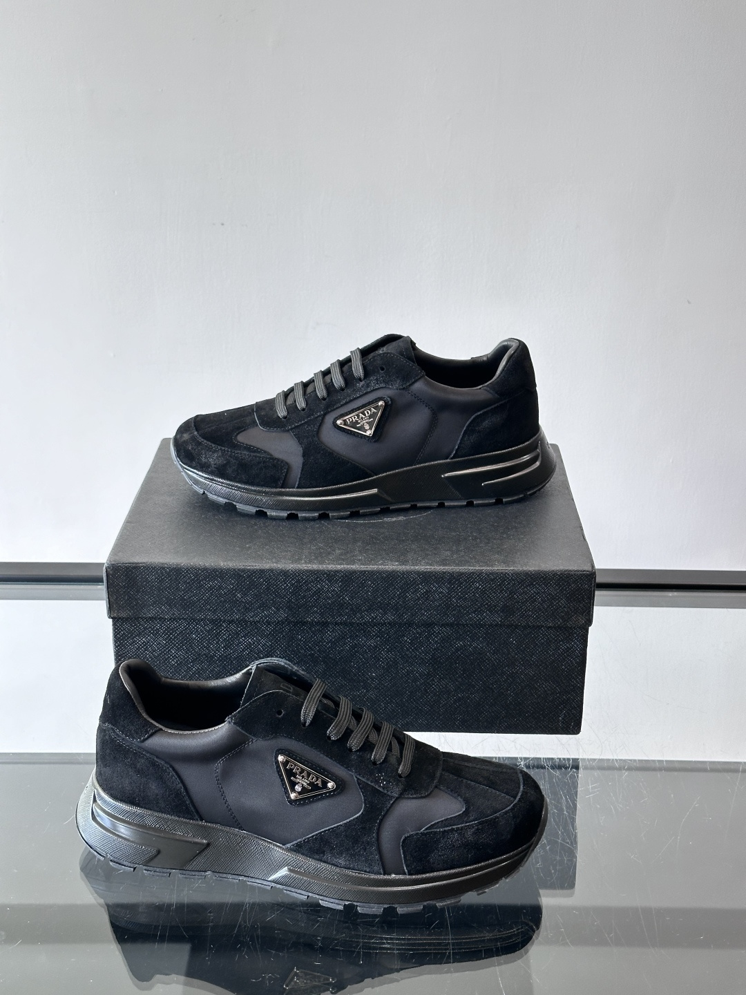 Prada 男士休闲运动鞋。采用麂皮与尼龙面料拼接，质感柔软又耐用，低调奢华。鞋侧三角徽标超有辨识度，橡