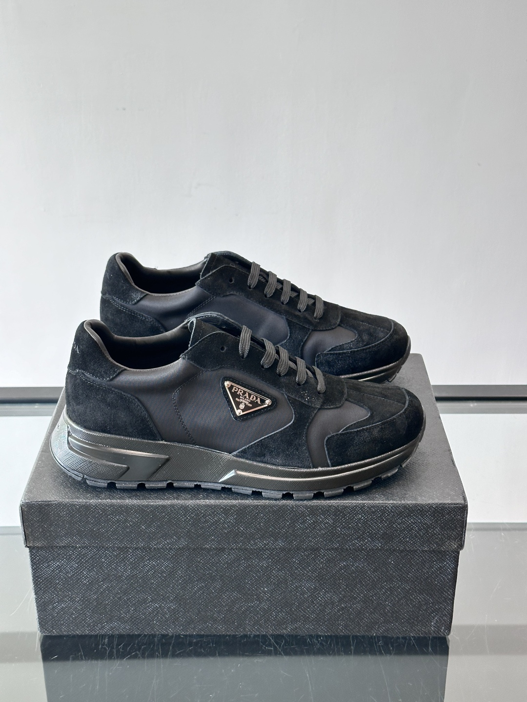 Prada 男士休闲运动鞋。采用麂皮与尼龙面料拼接，质感柔软又耐用，低调奢华。鞋侧三角徽标超有辨识度，橡
