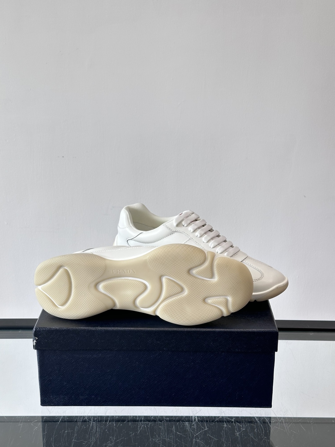 Prada 男士牛革运动鞋选用优质牛皮，鞋面光滑细腻，简约设计中融入品牌徽标，辨识度满分。橡胶鞋底轻便耐