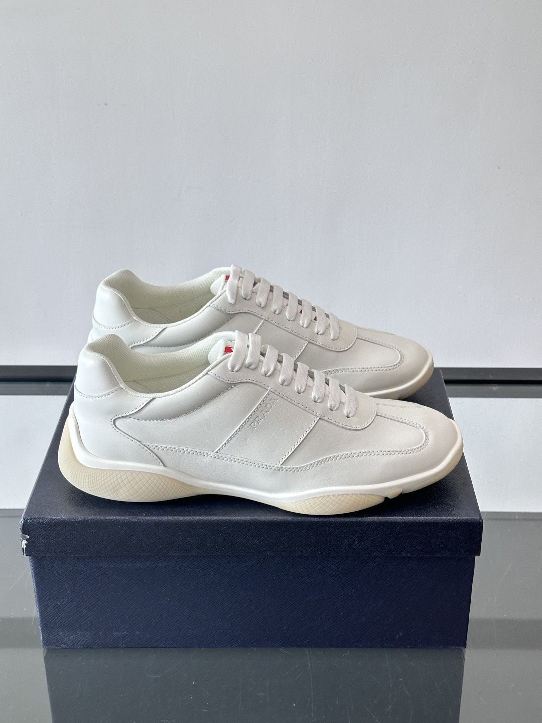 Prada 男士牛革运动鞋选用优质牛皮，鞋面光滑细腻，简约设计中融入品牌徽标，辨识度满分。橡胶鞋底轻便耐