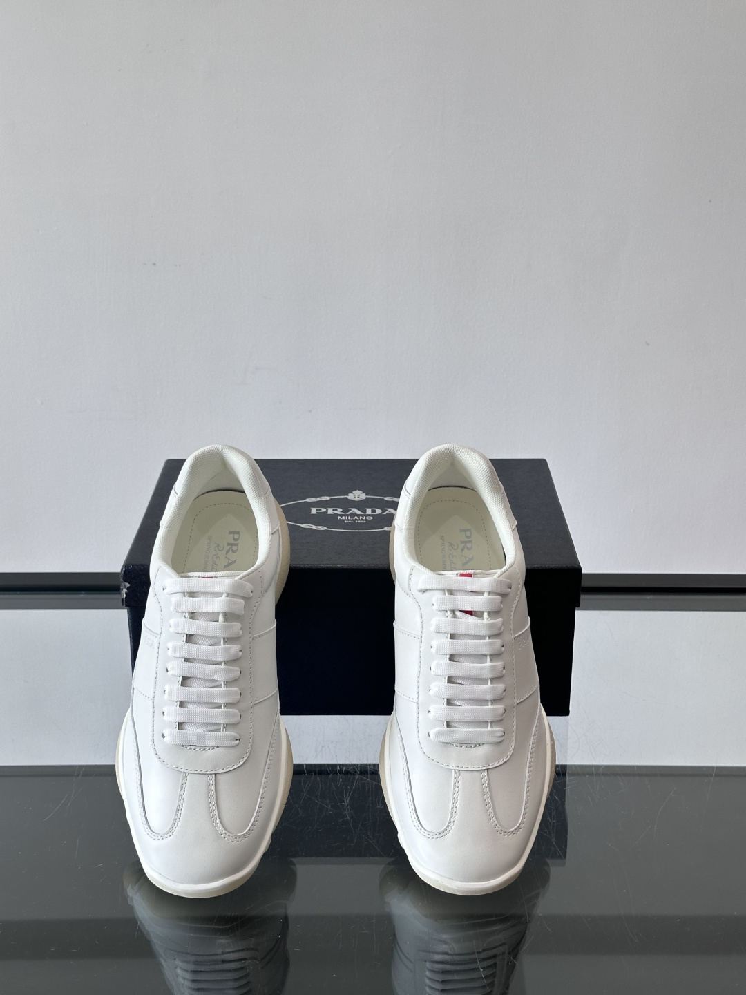 Prada 男士牛革运动鞋选用优质牛皮，鞋面光滑细腻，简约设计中融入品牌徽标，辨识度满分。橡胶鞋底轻便耐