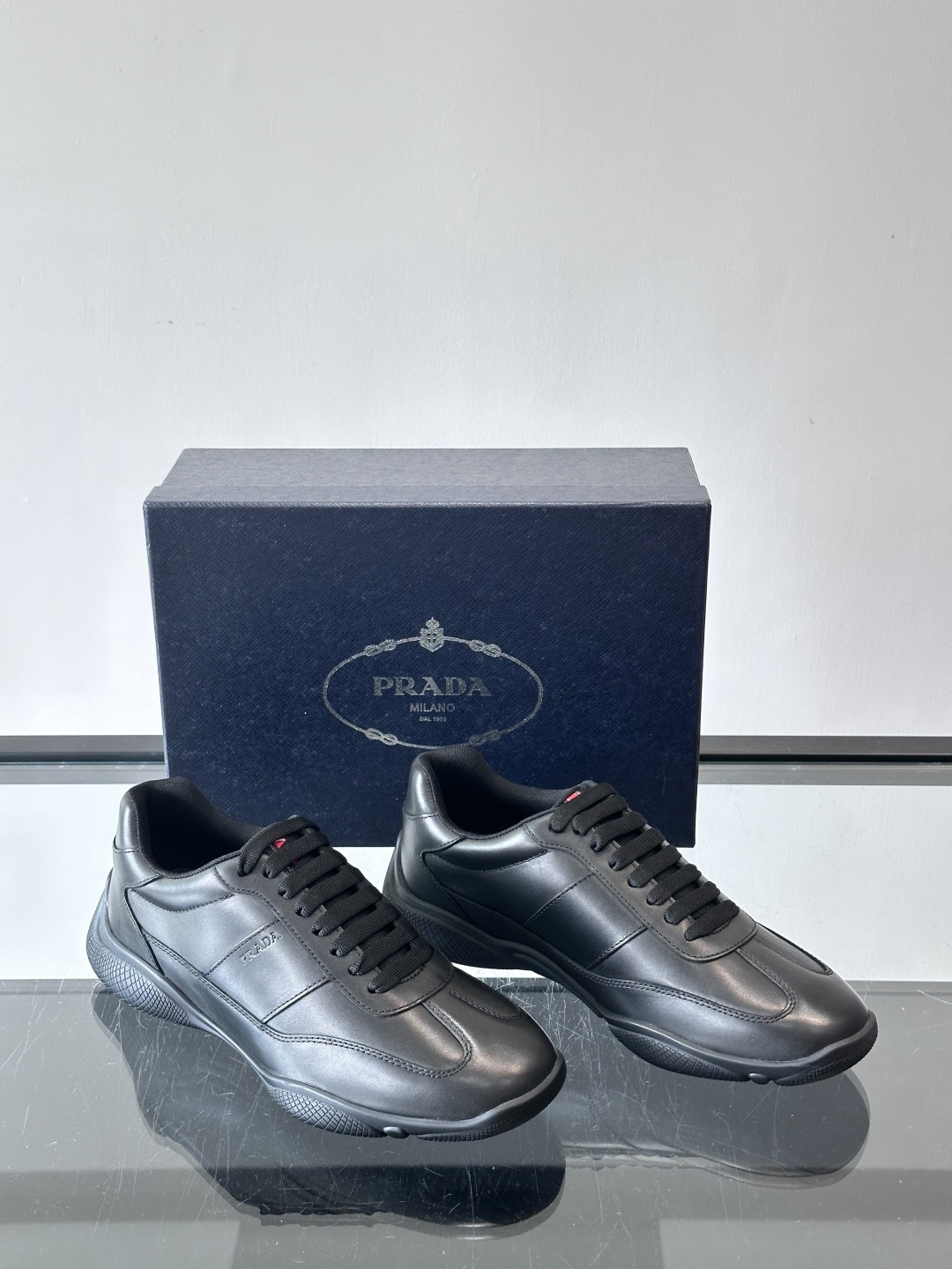 Prada 男士牛革运动鞋选用优质牛皮，鞋面光滑细腻，简约设计中融入品牌徽标，辨识度满分。橡胶鞋底轻便耐