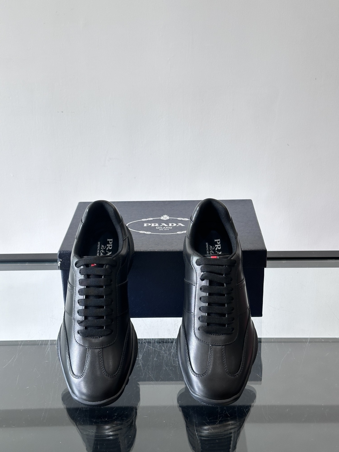 Prada 男士牛革运动鞋选用优质牛皮，鞋面光滑细腻，简约设计中融入品牌徽标，辨识度满分。橡胶鞋底轻便耐