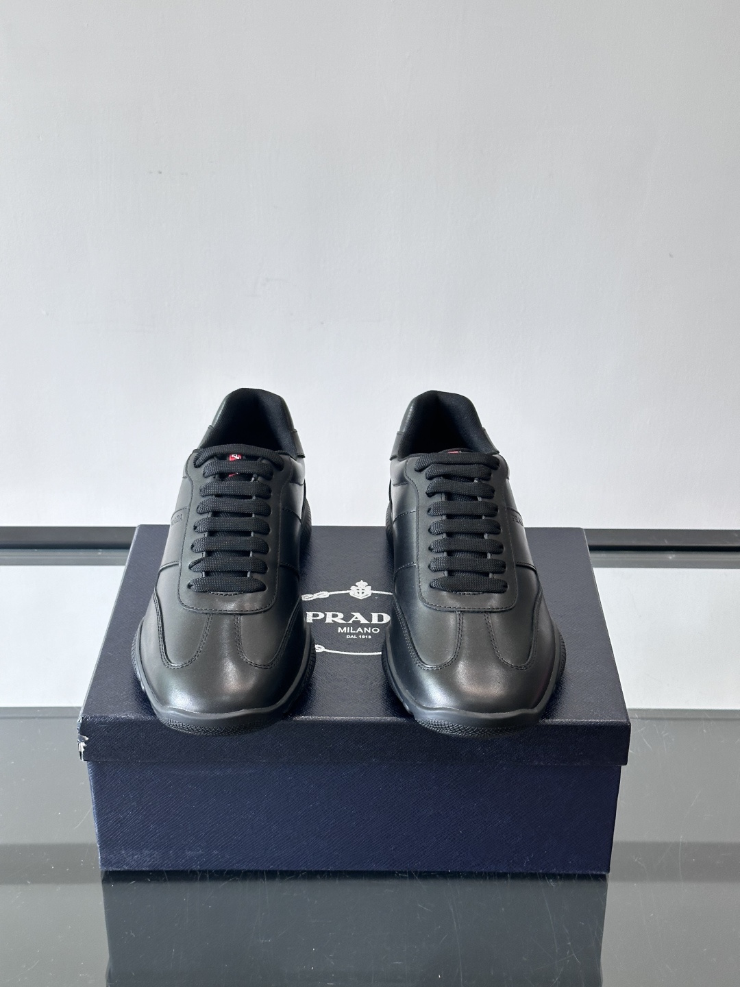 Prada 男士牛革运动鞋选用优质牛皮，鞋面光滑细腻，简约设计中融入品牌徽标，辨识度满分。橡胶鞋底轻便耐