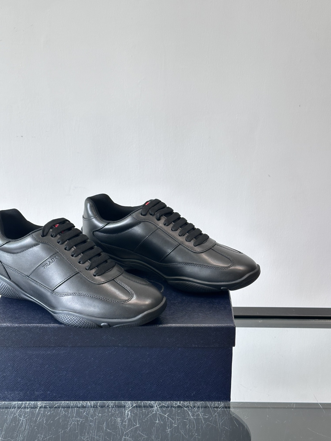 Prada 男士牛革运动鞋选用优质牛皮，鞋面光滑细腻，简约设计中融入品牌徽标，辨识度满分。橡胶鞋底轻便耐