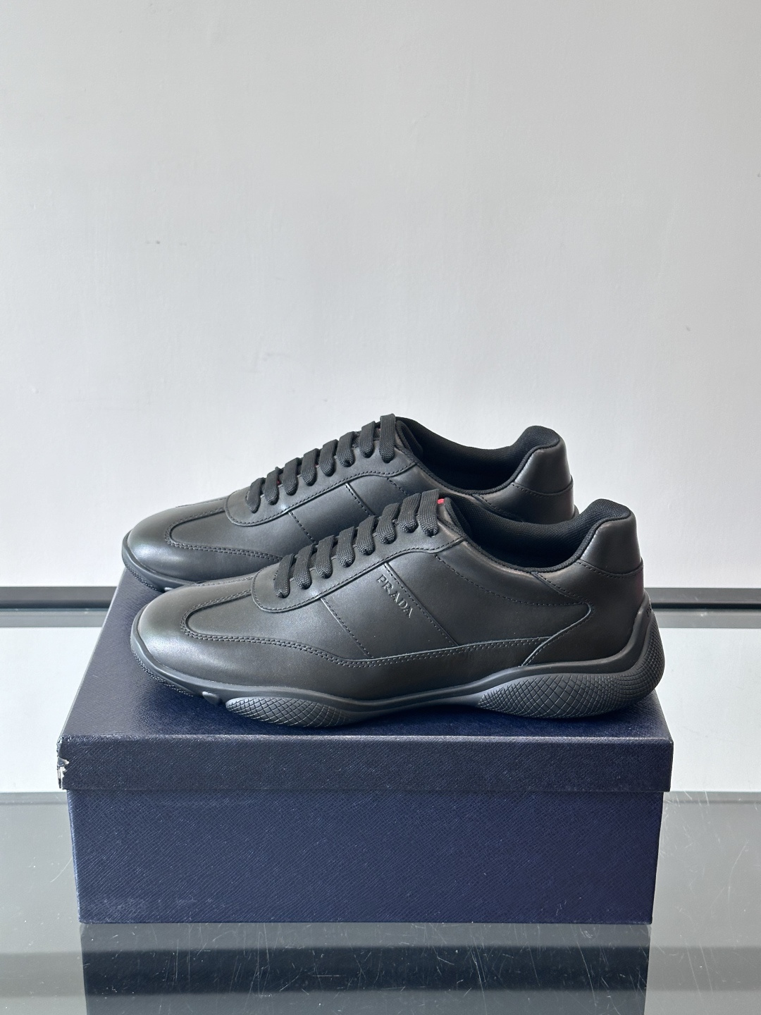 Prada 男士牛革运动鞋选用优质牛皮，鞋面光滑细腻，简约设计中融入品牌徽标，辨识度满分。橡胶鞋底轻便耐