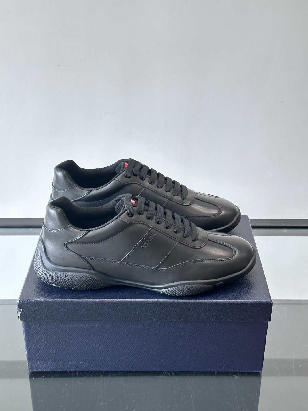 Prada 男士牛革运动鞋选用优质牛皮，鞋面光滑细腻，简约设计中融入品牌徽标，辨识度满分。橡胶鞋底轻便耐