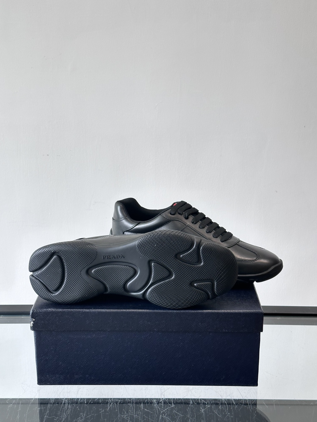 Prada 男士牛革运动鞋选用优质牛皮，鞋面光滑细腻，简约设计中融入品牌徽标，辨识度满分。橡胶鞋底轻便耐