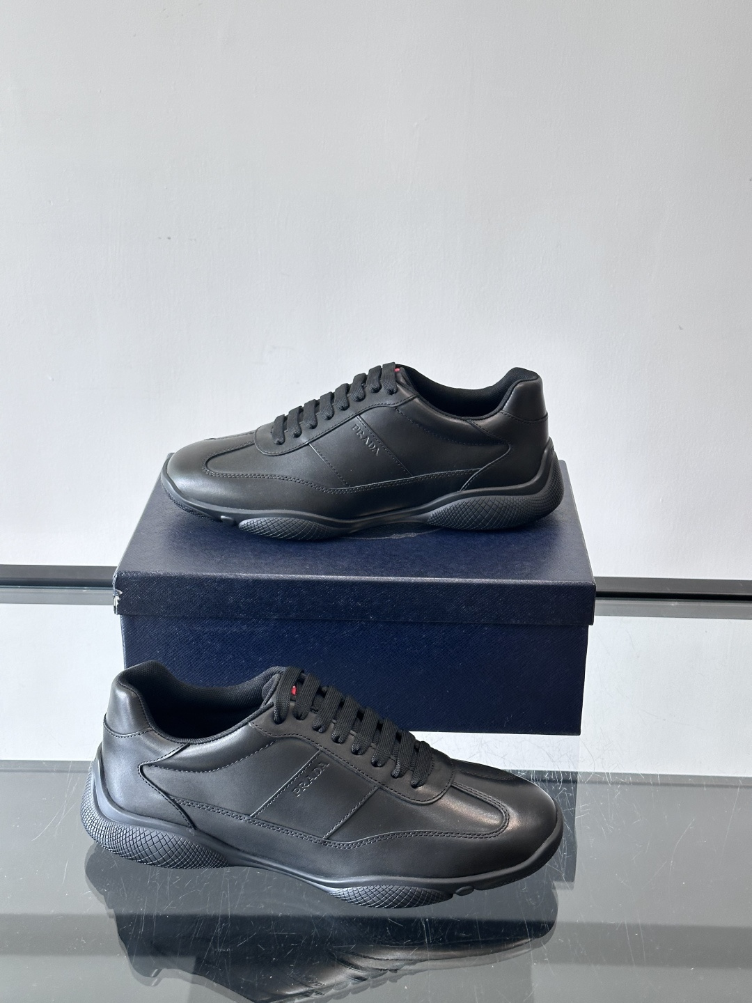 Prada 男士牛革运动鞋选用优质牛皮，鞋面光滑细腻，简约设计中融入品牌徽标，辨识度满分。橡胶鞋底轻便耐